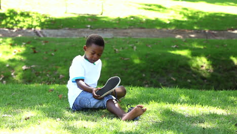 Little-boy-sitting-on-grass-taking-off-his-shoes