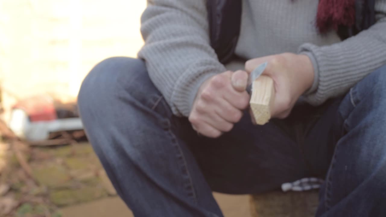 Woman carving a piece of wood with a knife