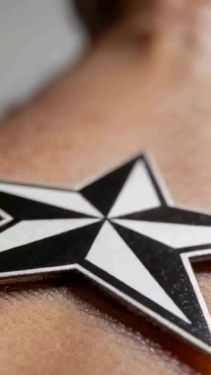 Vertical video: Panning camera revealing star pendant on chest in studio, showing bicolor pattern