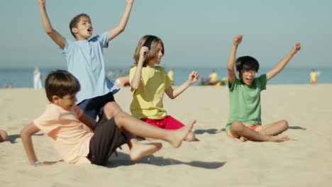 Side-view-of-excited-Caucasian-boy-kicking-ball-on-seashore