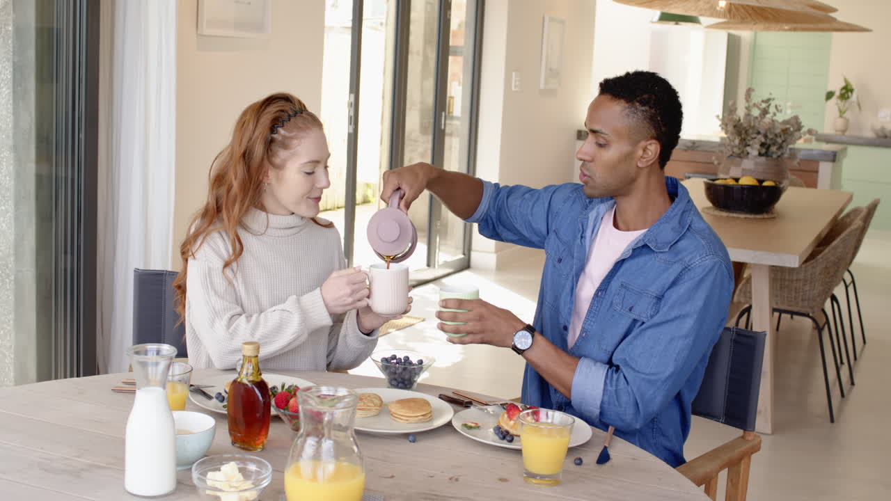 Couple enjoying breakfast together, pouring coffee and sipping from mugs