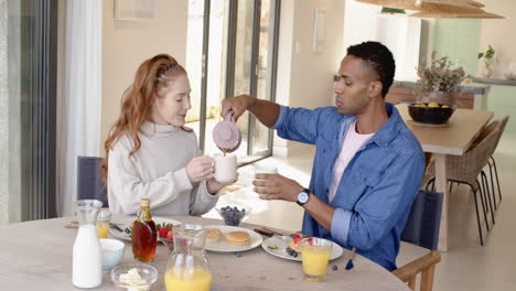 couple enjoying breakfast together, pouring coffee and sipping from mugs
