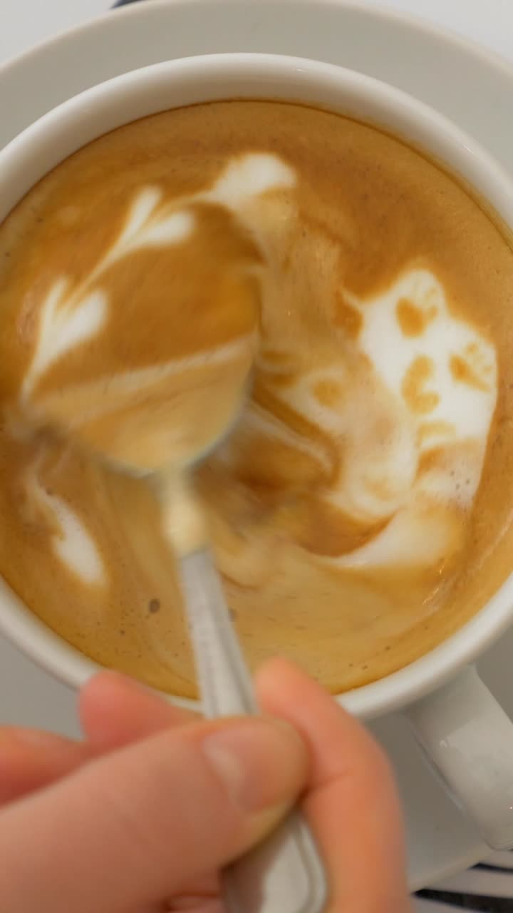 Versare lo zucchero e mescolare la latte art in una tazza di caffè