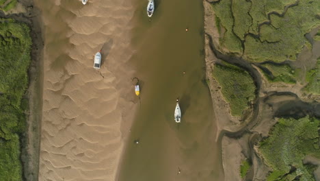 Drohnenschuss-Von-Oben-Nach-Unten,-Der-Bei-Ebbe-über-Den-Gezeitenbach-Fliegt,-Mit-Salzwiesen-Und-Segelbooten-In-Wells-next-the-sea,-North-Norfolk,-Großbritannien,-Ostküste