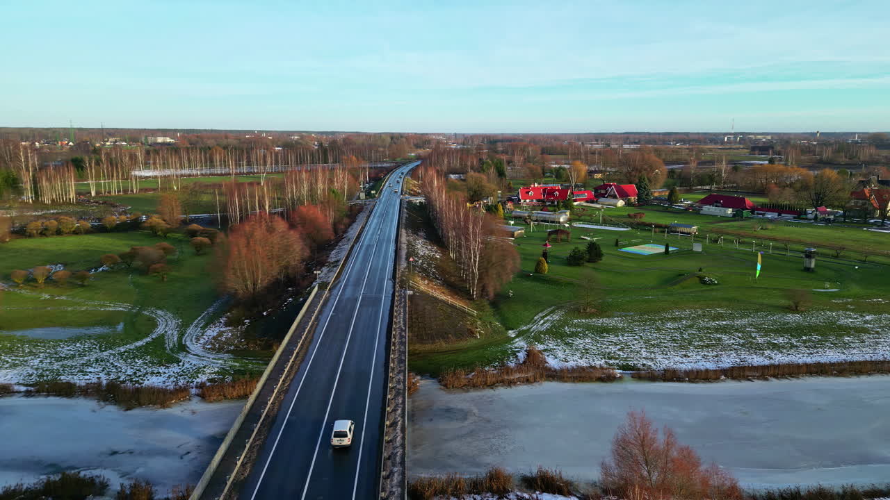 얼어붙은 강을 가로지르는 다리 위에 운전하는 자동차, 공중 드론 시각