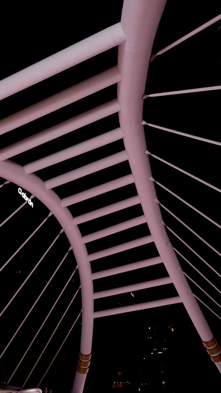 Camera tilts down revealing illuminated modern bridge architecture against dark Bangkok night sky