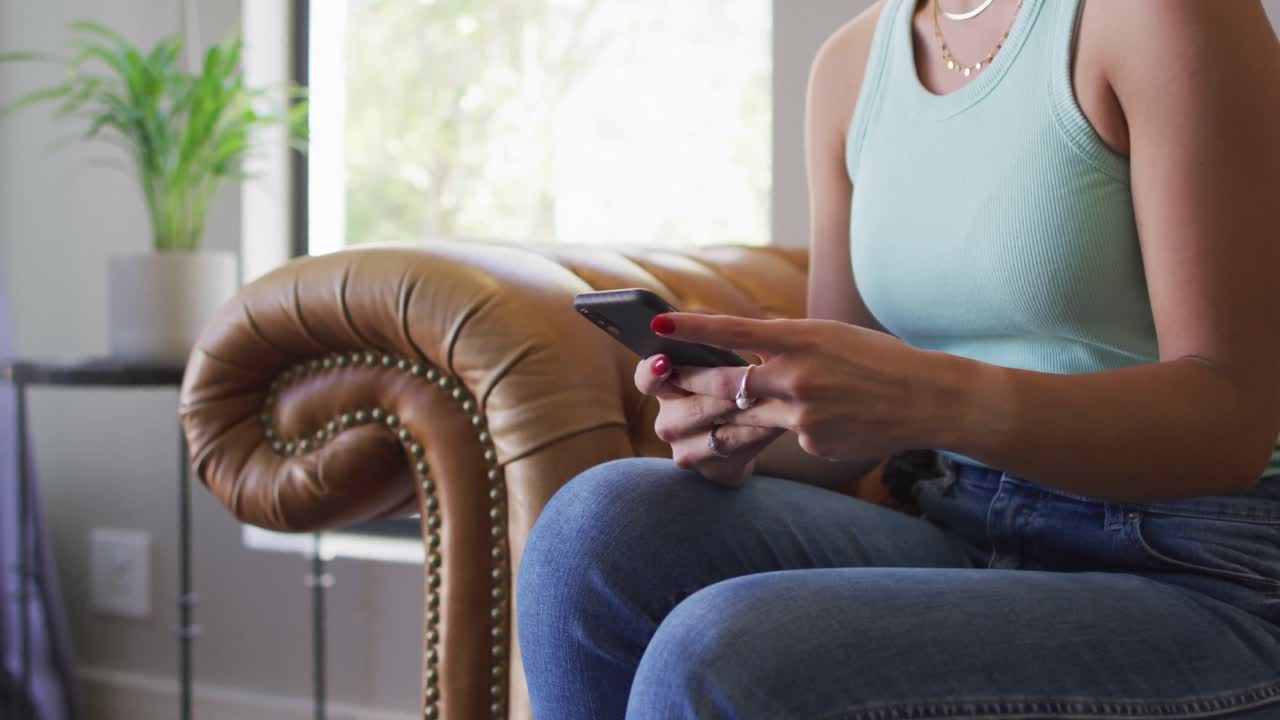 행복한 백인 여성이 집에서 시간을 보내고 스마트폰을 사용하고 있습니다.