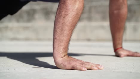 close up of a man doing push ups on the ground during daylight