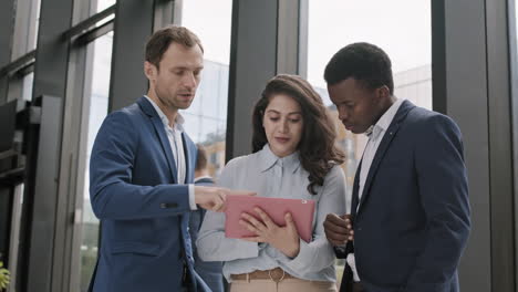 three diverse businesspeople using tablet in office
