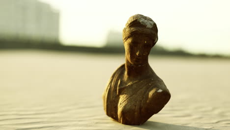ancient sculpture on sandy beach during golden hour creates serene atmosphere
