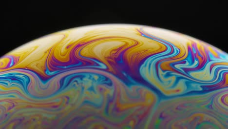psychedelic abstract planet from soap bubble on black background. light refraction on a soap bubble, vacro close up moving particles. rainbow colors on black background. slow motion