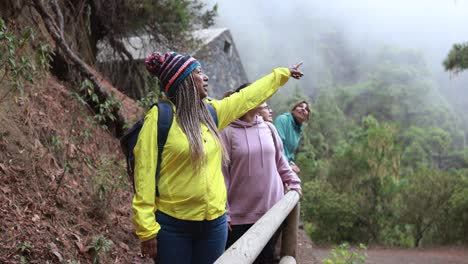 multiracial women having fun during trekking day in to the wood with stone house in background