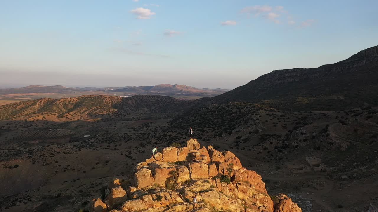 한 쌍의 남자와 여자 주위를 맴도는 공중 촬영은 햇빛을 받으며 정상에 함께 서 있다
