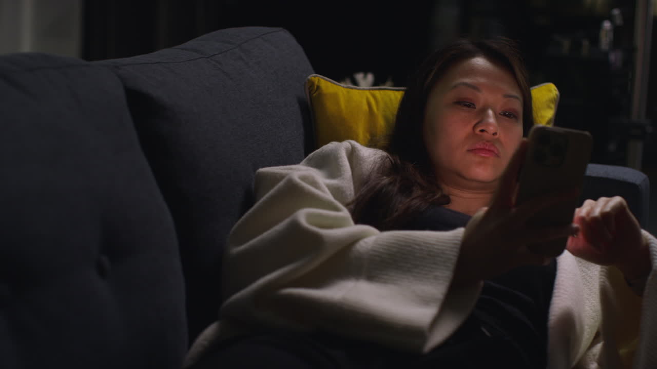 Close Up Of Woman Spending Evening At Home Lying On Sofa With Mobile Phone Scrolling Through Internet Or Social Media 7