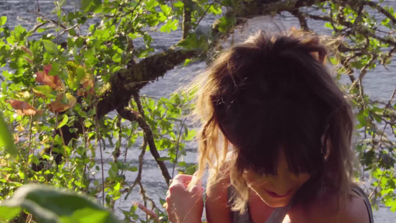 linda chica hipster arreglándose el pelo y hablando fuera de cámara en el parque