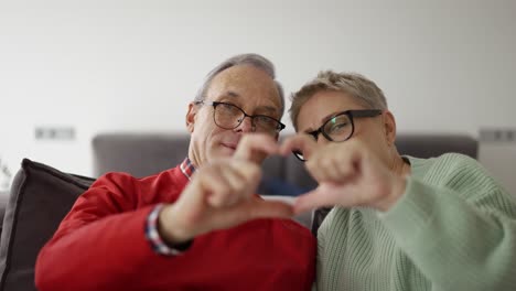 older retired couple making heart with their hands