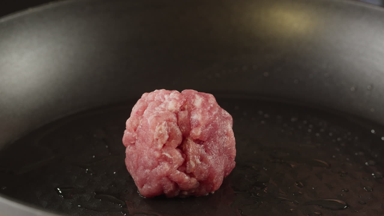 Preparing a meatball in a frying pan