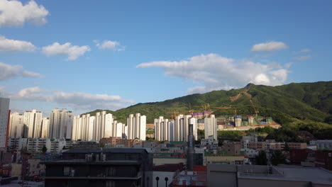 south korean apartment complex with mountains, blue sky and clouds in the background.