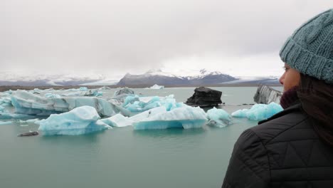 young adventurous woman overlooking iceberg lake in frozen landscape