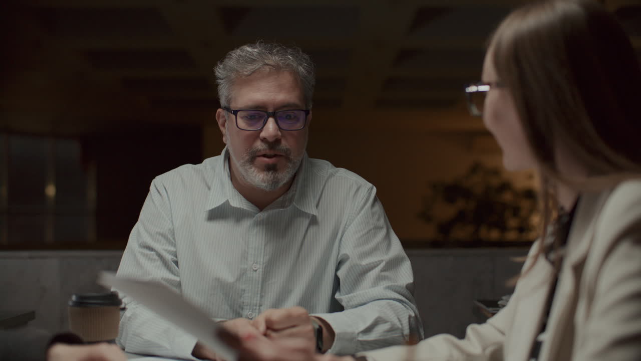 Businesswoman Discussing Document with Manager at Late Night Team Meeting