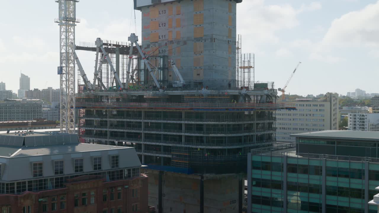 A wide-angle view of a high-rise construction site in Sydney, with workers scattered across multiple levels, capturing the city’s ongoing urban development.