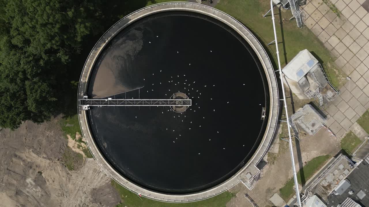 Top-down drone footage of a circular wastewater treatment tank with mechanical arm, part of the water infrastructure system near Volendam in the Netherlands. Vital for sustainable water purification