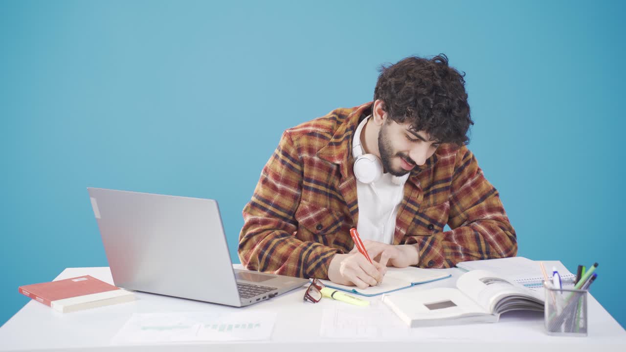 Male student working with laptop while doing homework and research.