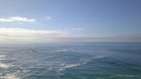 backwards shot showing waves crashing against the rocks and beach