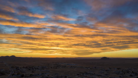 Die-Wolkenlandschaft-Des-Wüstenhimmels-Wird-Von-Der-Untergehenden-Sonne-Mit-Brillanten-Farben-Beleuchtet---Hyperlapse-Aus-Der-Luft