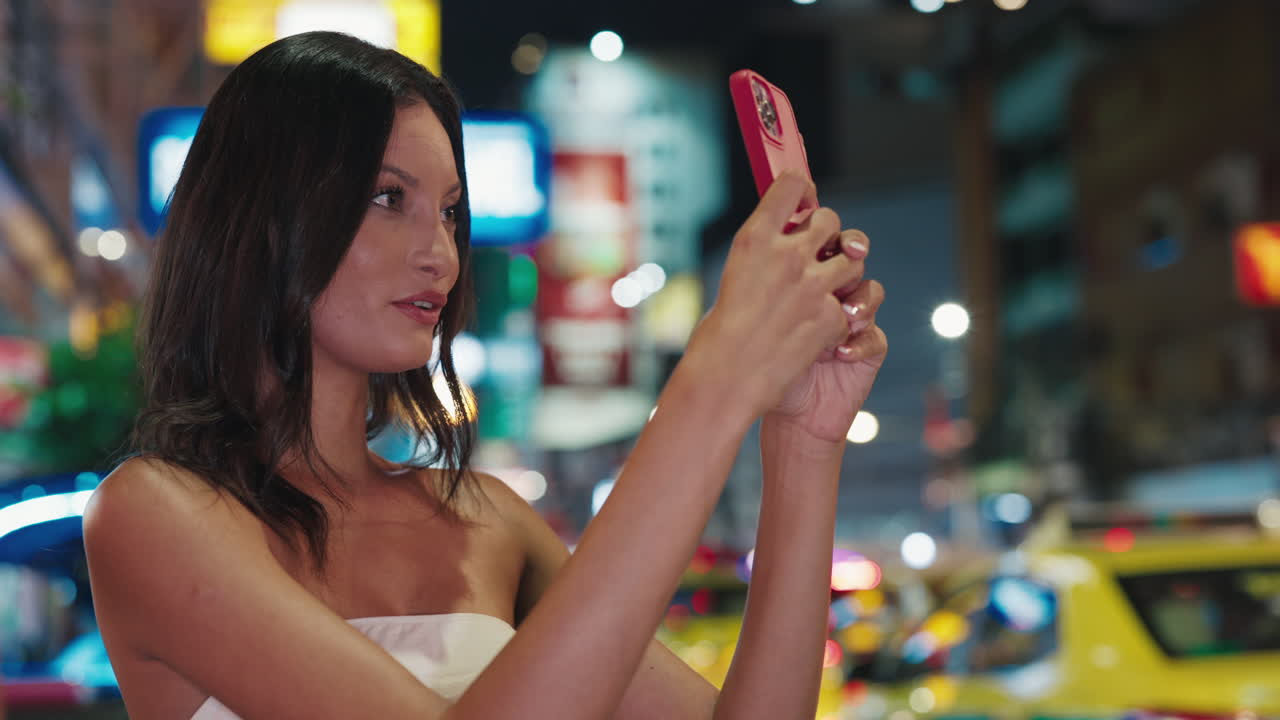 Woman taking photo at night in city street