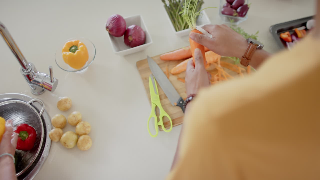 pareja diversa preparando y lavando verduras frescas en la cocina, cámara lenta