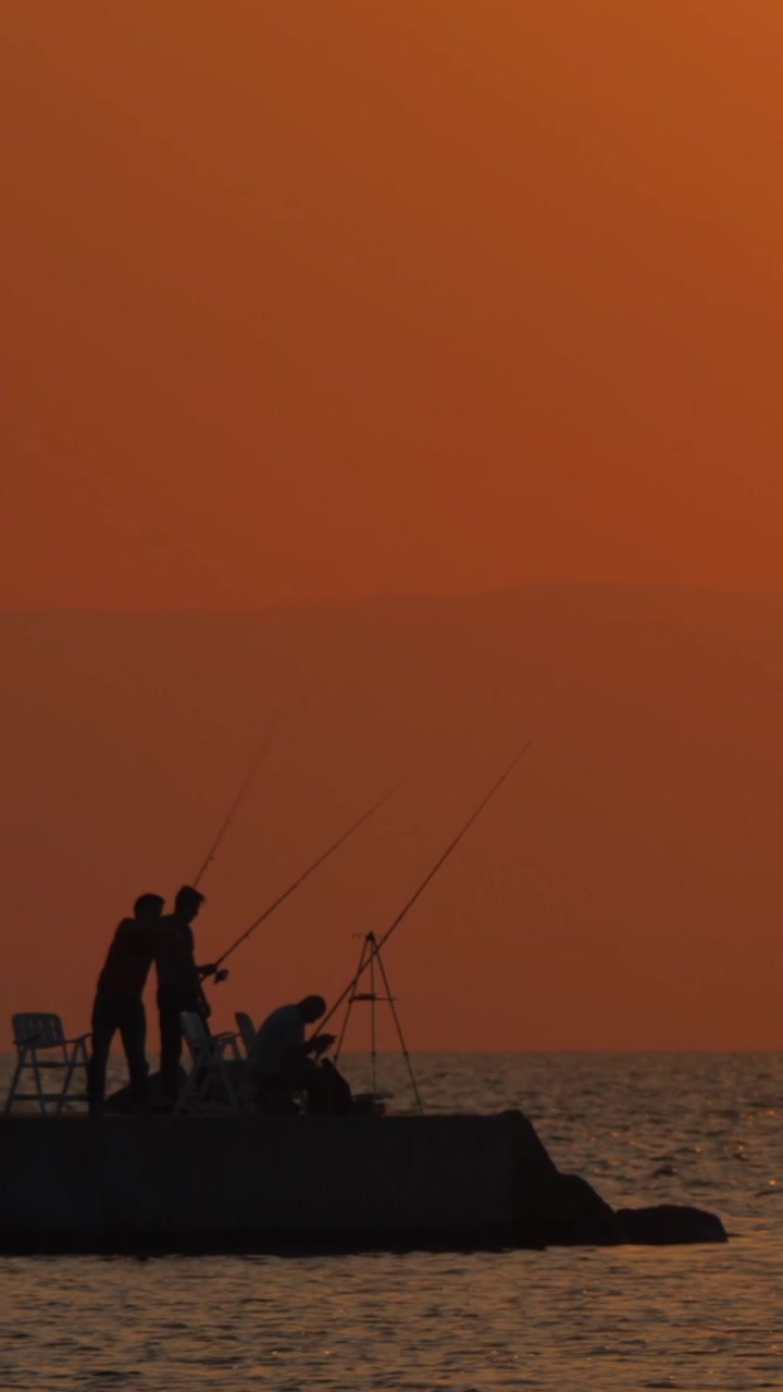 Escena vespertina de mar y pescadores en el muelle