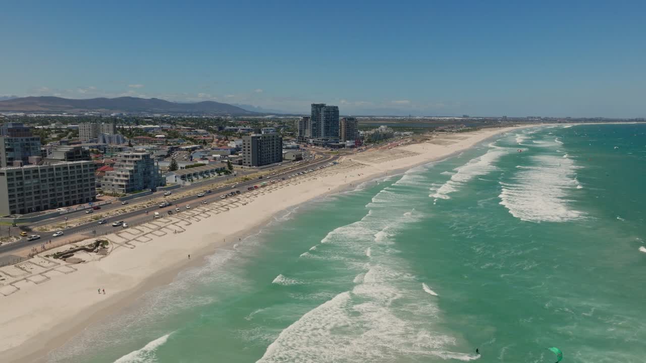 tomada de avión no tripulado de la playa principal y el bulevar de blouberg cerca de ciudad del cabo, con un kitesurfista al frente