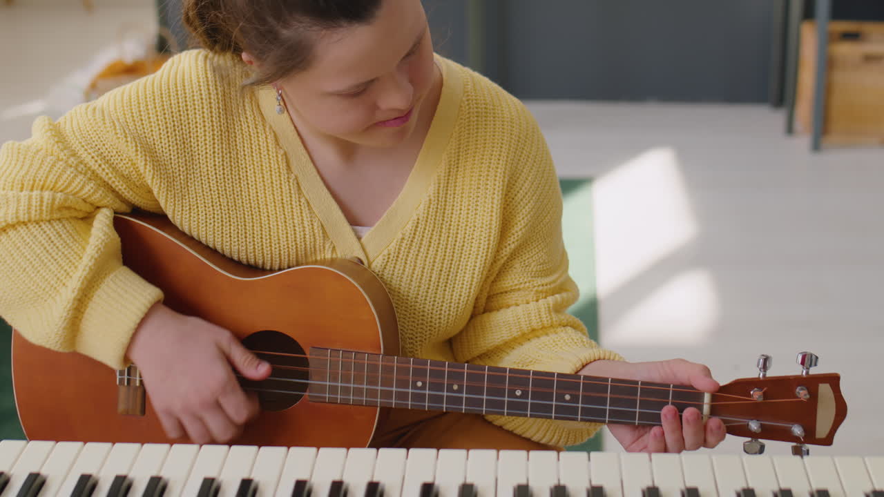 Girl with Down Syndrome Playing Guitar at Home