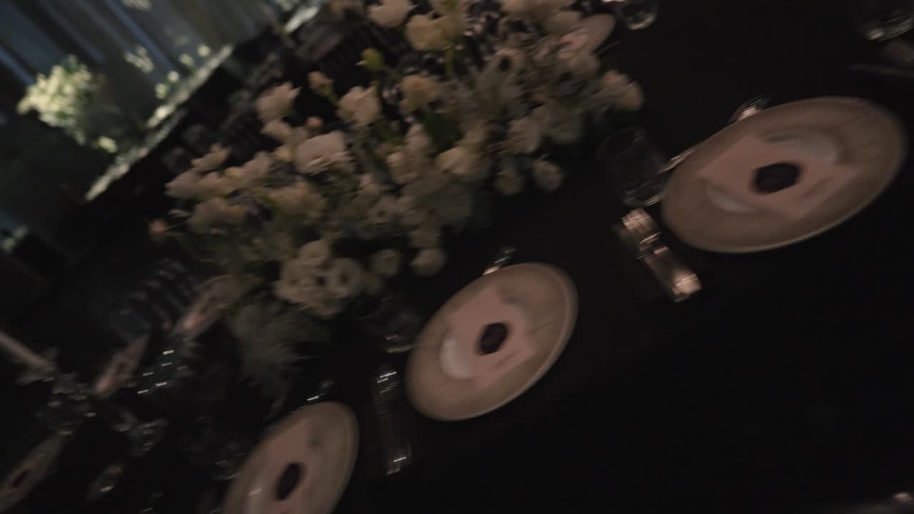 un movimiento de gimbal amplia toma de una sala de bodas, decoración de mesa de lujo, diseño de flores, interior de fantasía, candelabro luces decorativas, cámara lenta video en alta definición