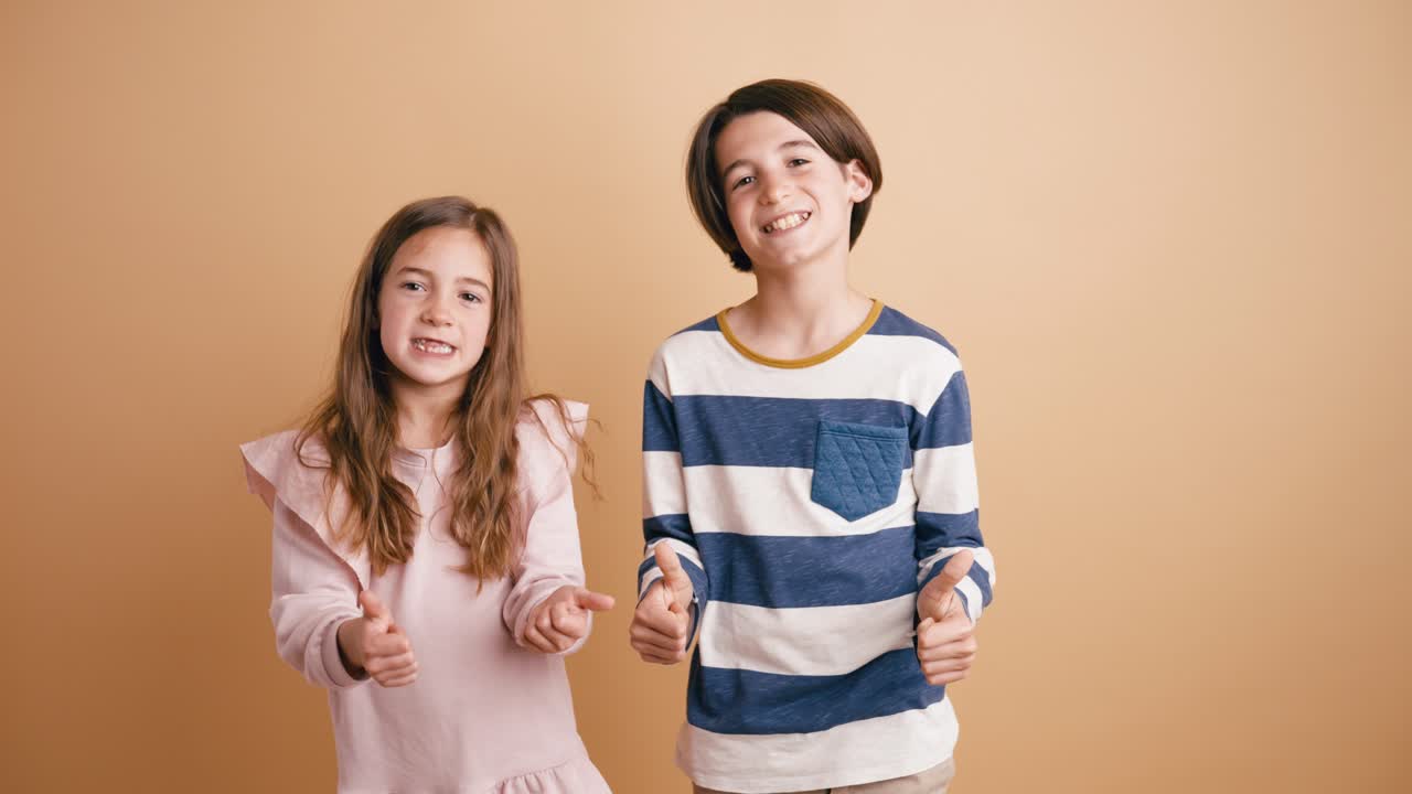 Bambini felici che sorridono e fanno il pollice in su in studio
