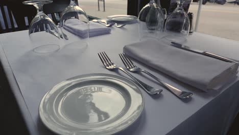 fine dining restaurant dinner table with settings on white table cloth steady slow-motion approach