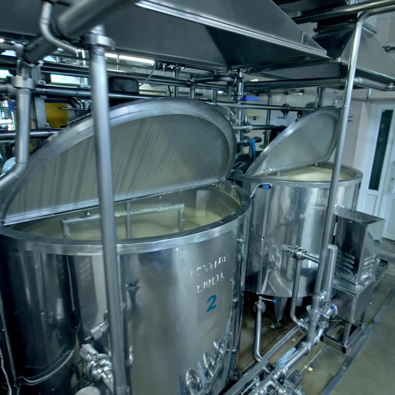 Three silver tanks for mixing milk products. Dairy production at the modern food factory. Steel tanks with open lids standing in row