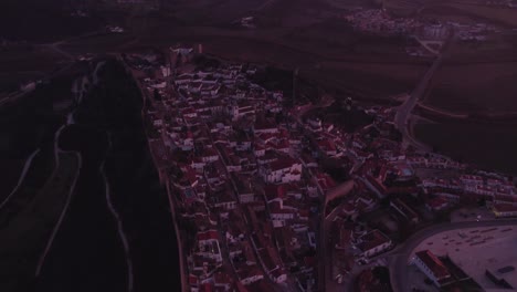 Reveal-shot-of-historic-walled-town-of-Obidos-Portugal-during-colourful-sunrise,-aerial