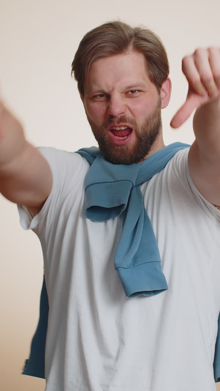 Ragazzo bello e scontento in T-shirt che mostra il gesto del pollice verso, segno di disapprovazione, insoddisfazione e antipatia