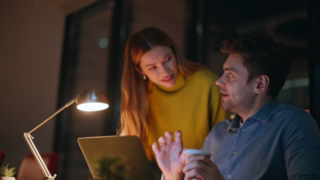 Startuper drinking coffee discussing project with woman at night office closeup