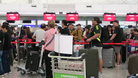 busy airport check-in area with travelers queuing at emirates counters