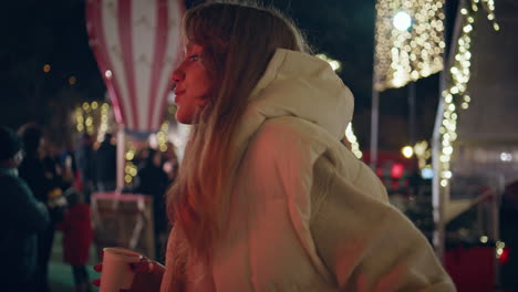 relaxed woman sipping hot drink at night festive market closeup. girl enjoying