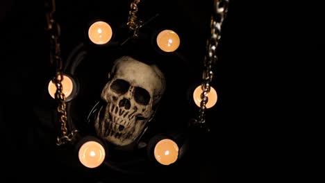 dummy human skull surrounded by candles on chains