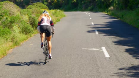 female cyclist cycling on a countryside road 4k