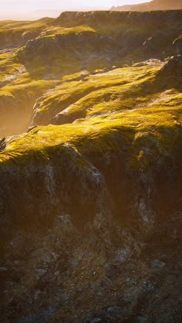 aerial view of a mountain landscape with cliffs and grassy hills