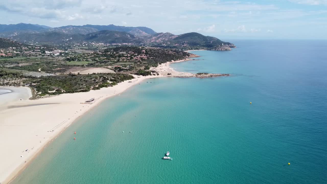 drone flight over the white sandy beach with crystal clear water in the bay of chia (sardinia), sunny!