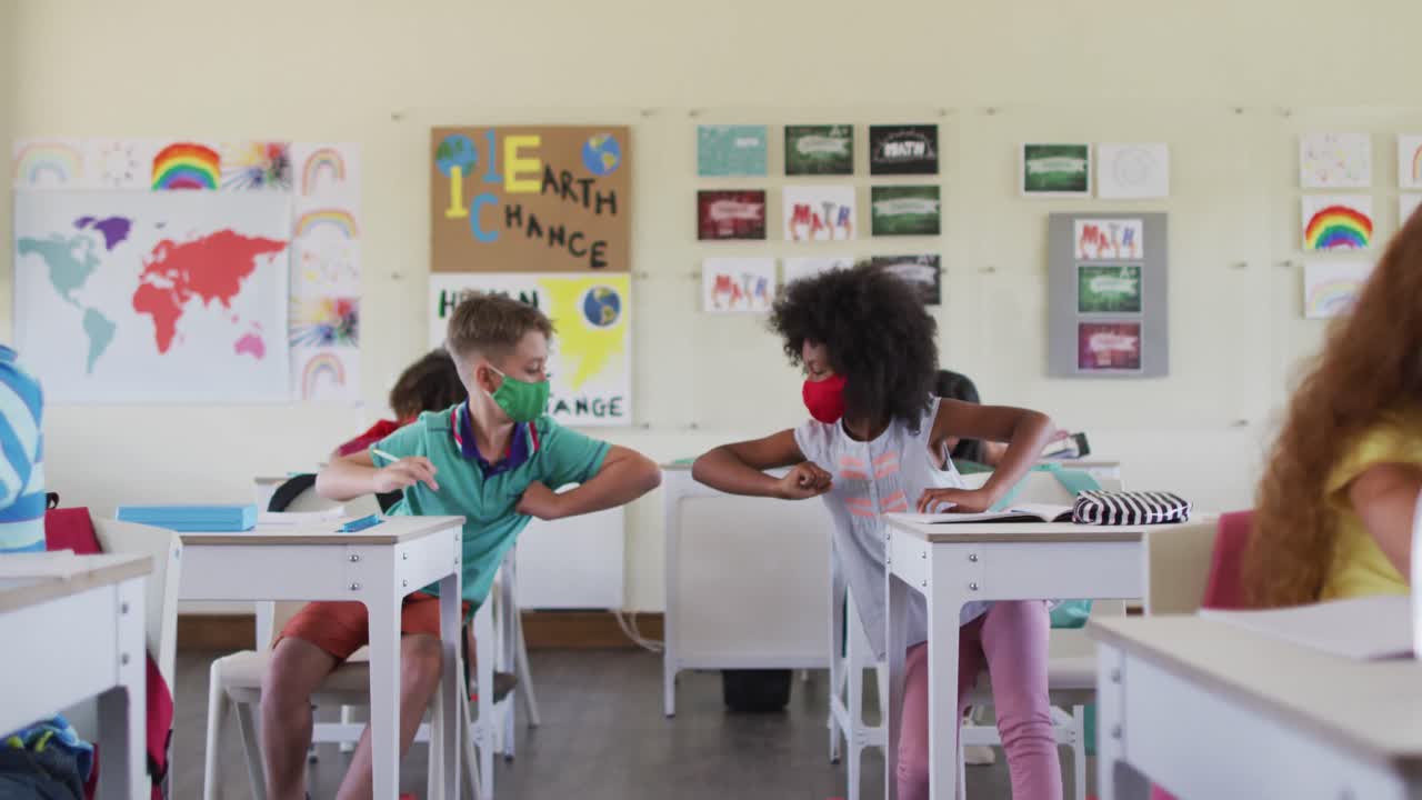 Two boys wearing face masks greeting each other by touching elbows at school