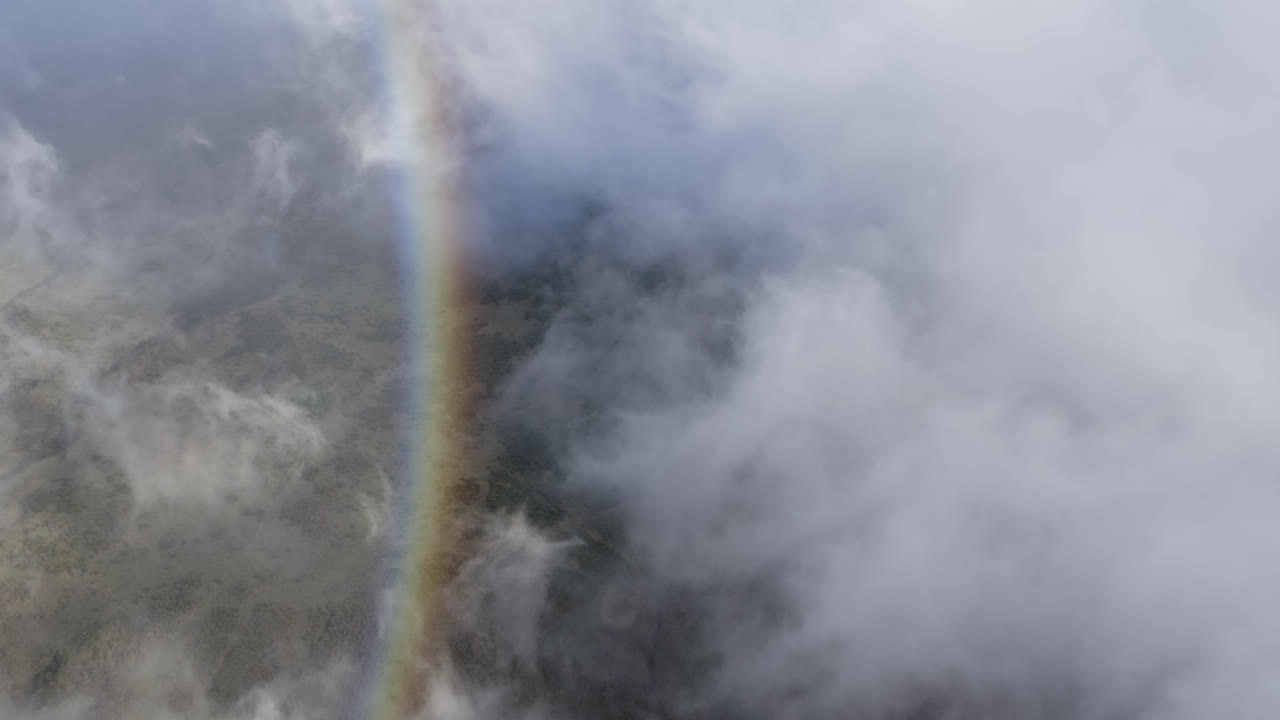 vista aérea de alto ángulo de nubes y un arco iris moviéndose sobre el volcán haleakala en maui, hawai