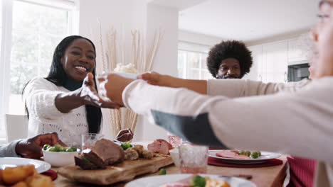 Familia-De-Raza-Mixta-De-Varias-Generaciones-Sentados-A-La-Mesa-Que-Sirve-La-Cena-Dominical-En-Casa,-De-Cerca,-De-ángulo-Bajo